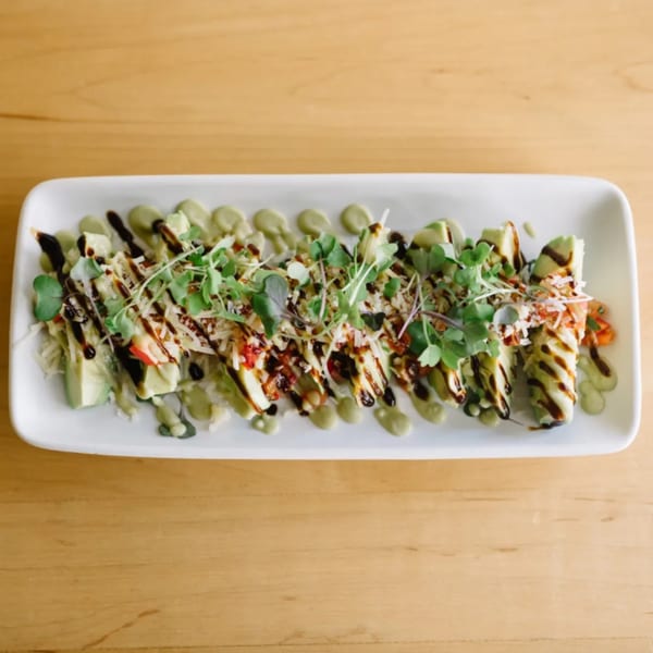 Good Kitchen's healthy avocado rolls with balsamic glaze, green sauce, and microgreens on a white plate.